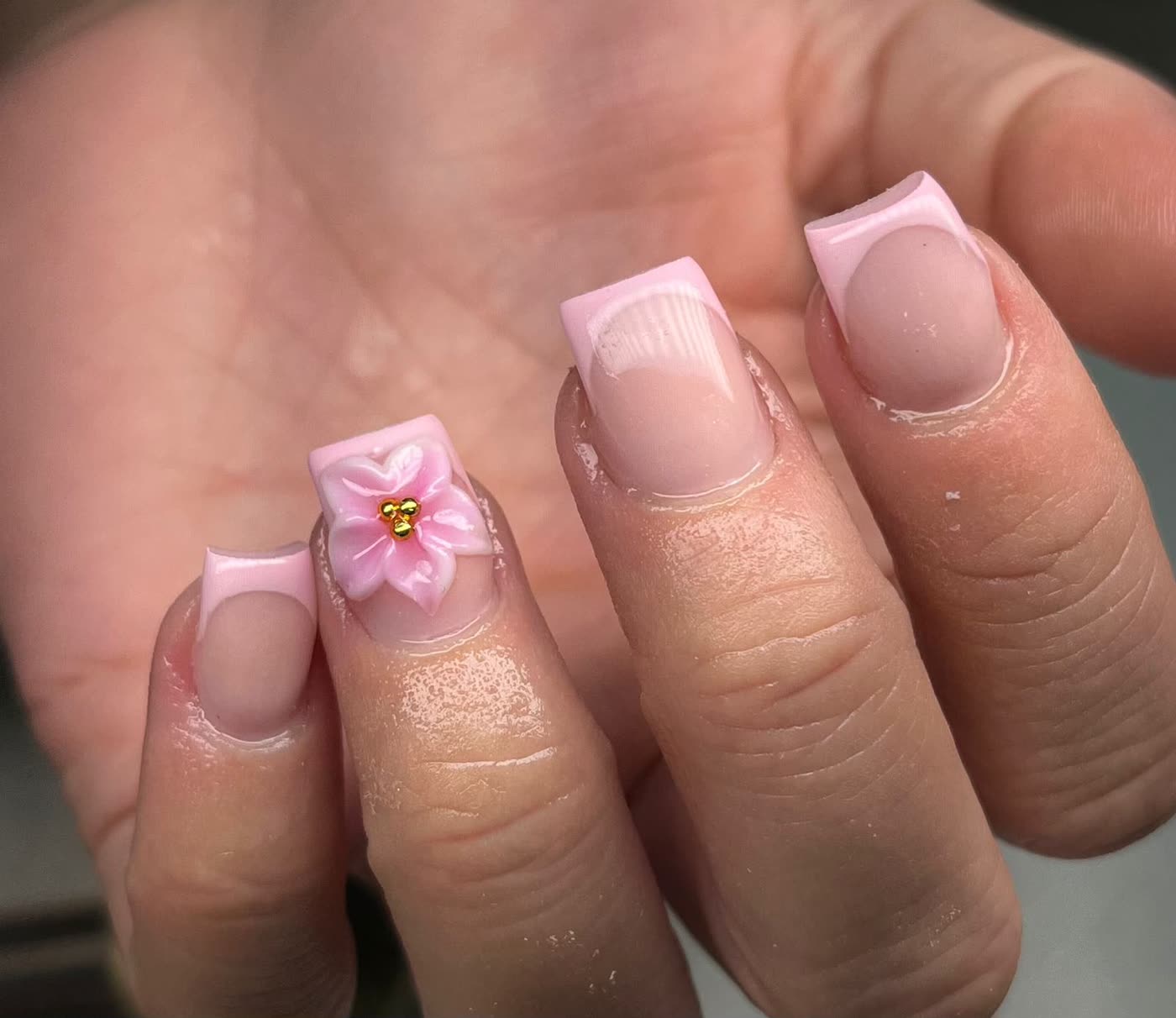 Roze french manicure met een 3D bloem en gouden kraaltjes