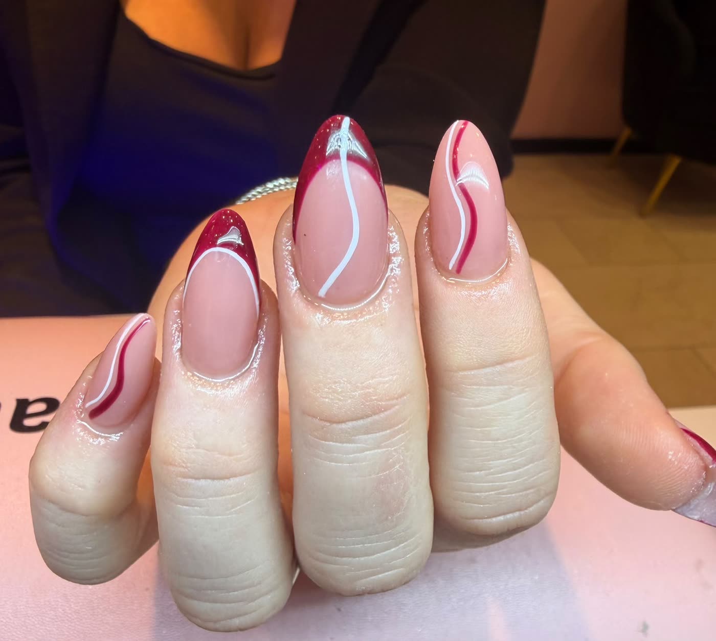 Nude nagels met een golvende donkerrode tip en witte lijnen